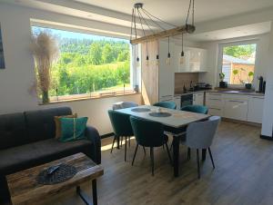 a kitchen and a living room with a table and chairs at Wonderland Apartamenty in Bukowiec