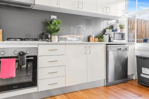 Una cocina con gabinetes blancos y electrodomésticos de acero inoxidable. en 2 Bedroom House Woolloomooloo, en Sídney 15 fotos más