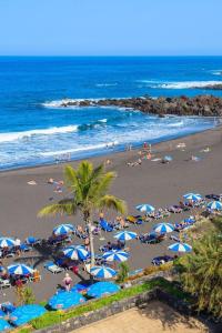una spiaggia con un mucchio di persone e ombrelloni di Charming Canarian House at Villa Lila a Puerto de la Cruz
