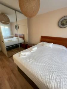 une chambre avec un lit blanc et un miroir dans l'établissement Amplio apartamento, playa, tren, à Malaga