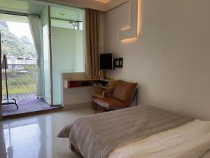 una camera da letto con un letto, una sedia e una finestra di Yangshuo Durian Guesthouse 阳朔榴莲间民宿 a Yangshuo