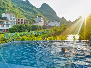 una persona che nuota in una piscina con montagne sullo sfondo di Yangshuo Durian Guesthouse 阳朔榴莲间民宿 a Yangshuo