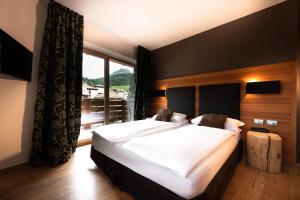 a bedroom with a large bed and a large window at Sport Hotel S. Vigilio in Moena