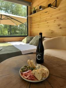 eine Flasche Wein und ein Teller mit Essen auf dem Tisch in der Unterkunft глемпінг Обійми in Yatski