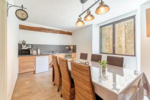a kitchen with a table and chairs and a clock on the wall at La Bonbonnière Gîte De Charme in Malaucène +16 photos