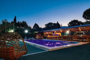 a swimming pool in front of a restaurant at night at Apollon Garden Pamukkale in Denizli