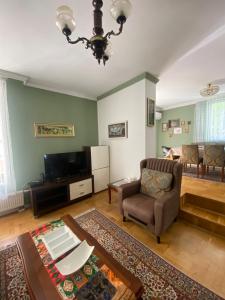 a living room with a couch a chair and a television at Holiday Home Ilidza Rose in Sarajevo