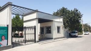 a small white building with a gate on a street at MILLIY Hostel in Jizzax