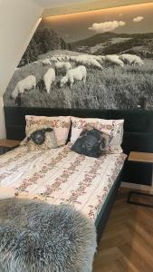 a bed with a painting of sheep in a field at Apartament u Jagi Sądelska 119f in Murzasichle