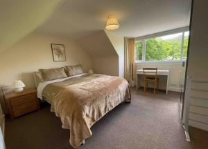 Un dormitorio con una cama y un escritorio y una ventana. en Wood Cottage, en Peebles