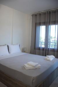 a white bed with two towels on it with a window at Buena Vista - San Mames in Agios Mamas