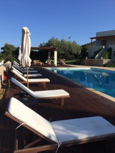 a swimming pool with lounge chairs and an umbrella at Xenon Estate in Spetses
