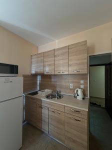 a kitchen with wooden cabinets and a sink and a refrigerator at goldenseaview apartment 2 in Pomorie