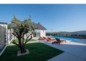 a pool with benches and a tree in a yard at Luxury Grey house in Stolac