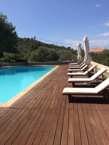 a row of lounge chairs with umbrellas next to a swimming pool at Xenon Estate in Spetses