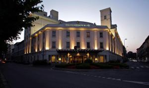 Un grand bâtiment blanc avec des lumières sur lui dans l'établissement Grand Visconti Palace, à Milan