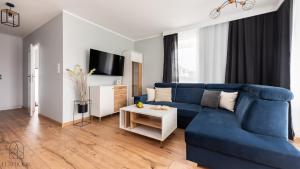 a living room with a blue couch and a table at Flatbook Apartamenty - Sztutowo Baltic Sun 2 z parkingiem in Sztutowo +29 photos