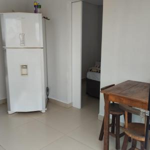 une cuisine avec un réfrigérateur blanc et une table dans l'établissement Estúdio Vênus, à Alto Paraíso de Goiás 2 autres photos