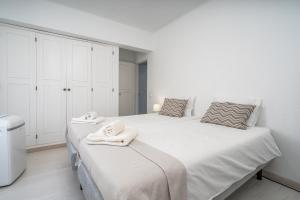 two beds in a white room with towels on them at Casa Terrace Carvoeiro in Carvoeiro