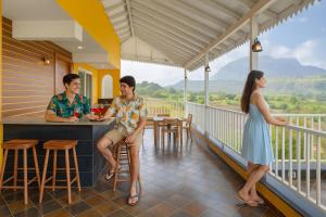 three people sitting at a bar on the balcony of a house at EKOSTAY - Casa Den in Igatpuri