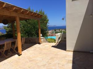 a patio with a wooden pergola and a table and chairs at Xenon Estate in Spetses
