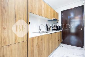 Bloomfields Fabulous Stu In Al Maryah في أبوظبي: مطبخ مع خزائن خشبية وطاولة عمل