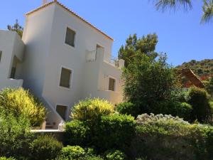 a white house surrounded by trees and bushes at Xenon Estate in Spetses