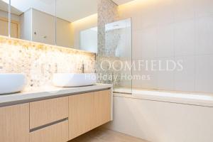 La salle de bains est pourvue de 2 lavabos et d'une baignoire. dans l'établissement Bloomfields Cozy 1br Mayan with Beach Access, à Abu Dhabi