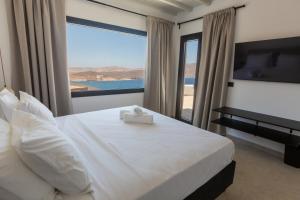 a bedroom with a white bed with a large window at HoM Mykonos - Seaview Villa with private pool in Mýkonos City