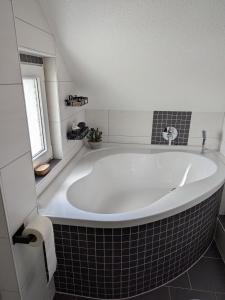 a large white tub in a bathroom with a window at Ferienwohnung Teichblick in Altenburg