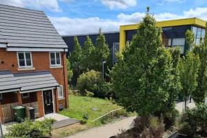 a house and a tree in front of a building at Spacious 3-Bed House - Sleeps 8 Garden & Parking in Peterborough