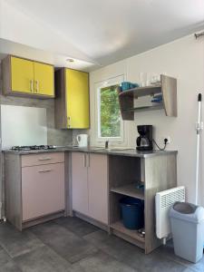 a kitchen with yellow and pink cabinets and a window at Camp Les Deux in Jouillat