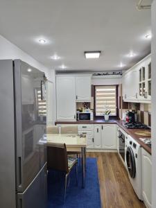 a kitchen with white cabinets and a table and a dining room at Central Apartment in Petroşani