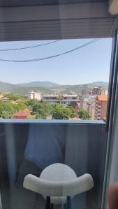 a white chair in a window with a view at Nikolas apartment in Mitrovica +5 photos