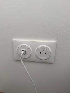 Un tomacorriente blanco en una pared con un cable enchufado. en Royal appart city 1, en Calais