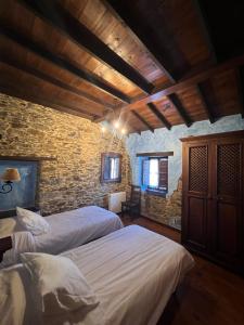 a bedroom with two beds and a stone wall at La Casona del Cura 2, LIRIO in Pravia
