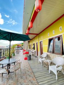 a patio with chairs and tables and an umbrella at WISMA SUNRISE GUEST HOUSE 10 minutes by walking to the big fruit market in Berastagi in Berastagi