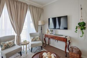 a living room with a tv and a desk and chairs at Unwind at Coral Bright 2BR Beach Apartment in Bloubergstrand