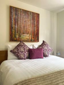a large painting above a bed with purple pillows at Westminster College Cottages, Cambridge in Cambridge +10 photos