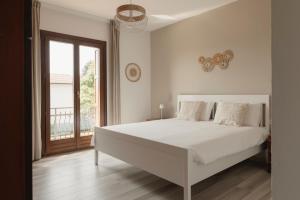 a white bedroom with a large bed and a window at Casa Ferrant in Faloppio