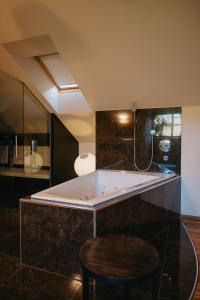bagno con vasca e sgabello. di Hotel Albizia a Jennersdorf