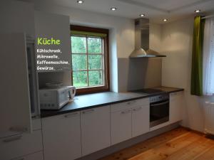 kuchnia z białymi szafkami i oknem w obiekcie Ferienhaus Huber w mieście Mariapfarr