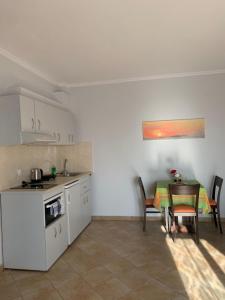 a kitchen with a table and a small kitchen with white cabinets at Dilina Studios in Arkasa