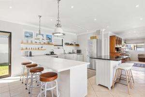 una cocina con una gran isla blanca con taburetes de bar en 8 on Nivenia by Host Agents, en Bettyʼs Bay