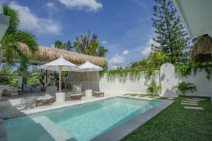 - une piscine avec des chaises et des parasols à côté d'une villa dans l'établissement Villa Nair NEW stylish 3BR Canggu with large pool, projector & green field view, à Canggu