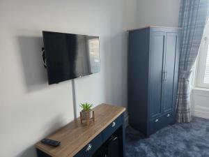 a room with a tv on a wall with a dresser at Musselburgh Links B&B in Musselburgh
