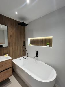 Un baño con una gran bañera blanca y un lavabo. en Ski In-Ski Out Luxe Chalet Apartment in Arc 1950 - Newly Renovated, en Arc 1950