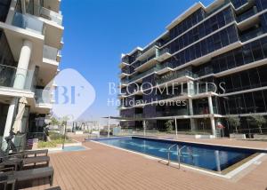 un gran edificio de apartamentos con piscina frente a él en Bloomfields 1Br Golfside Getaway Damac Hills, en Dubai Marina