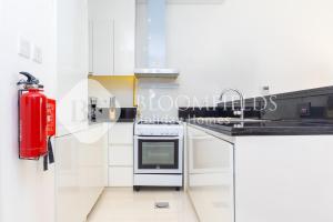 Una cocina con gabinetes blancos y un extintor rojo. en Bloomfields 1Br Golfside Getaway Damac Hills, en Dubai Marina