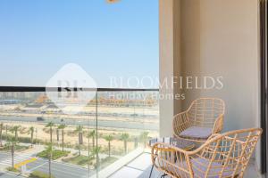 Un balcón con dos sillas y vista a la playa. en Bloomfields 1Br Golfside Getaway Damac Hills, en Dubai Marina
